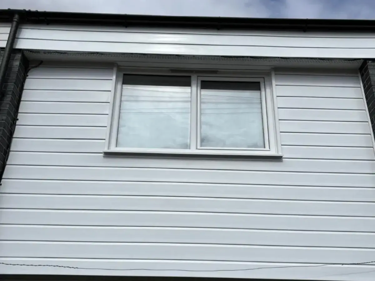 White horizontal cladding installed across an upper-storey wall around a white-framed window. By Norfolk Exterior Solutions.